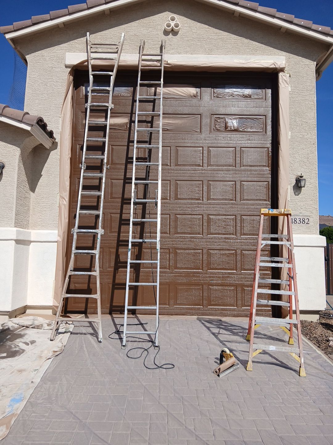 Masked garage door and ladders set up at a Goodyear home during painting