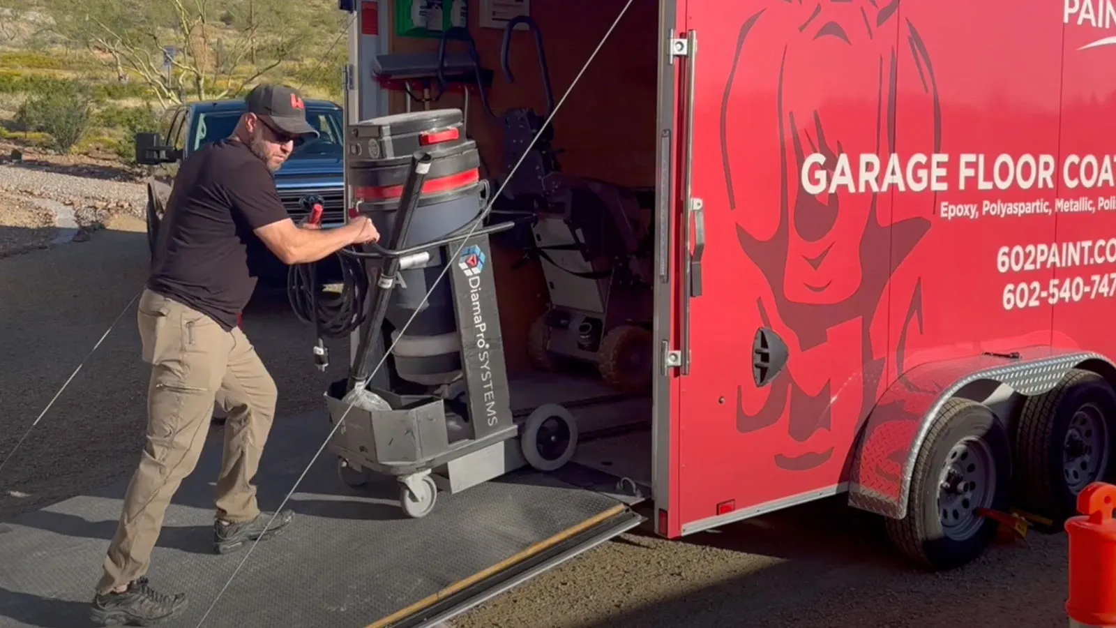 Crew member unloading a dust extraction vacuum from the garage floor coatings trailer