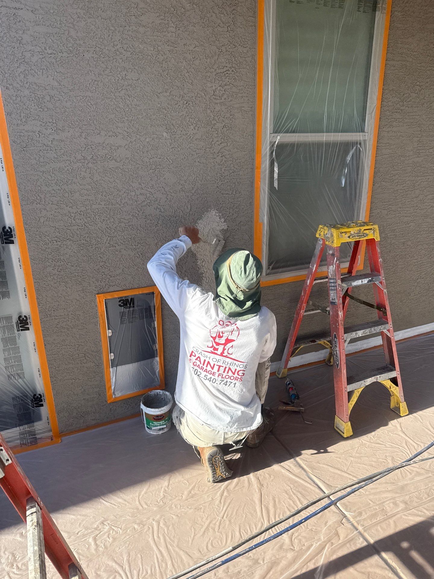 Crash of Rhinos crew member patching stucco on a Gilbert home