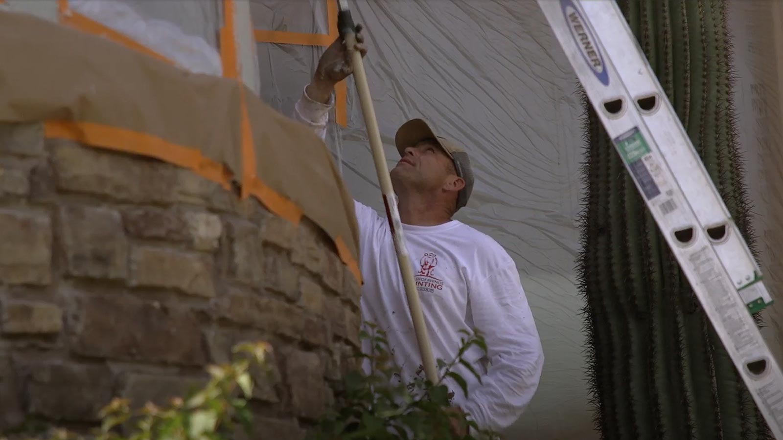 Crash of Rhinos painter rolling a masked exterior wall in Phoenix