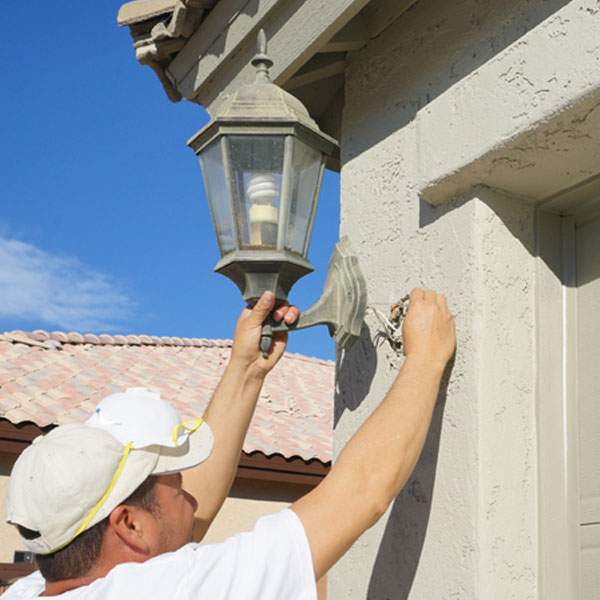 Having completed the job, our painter re-attaches a light fixture to the outside of the home.