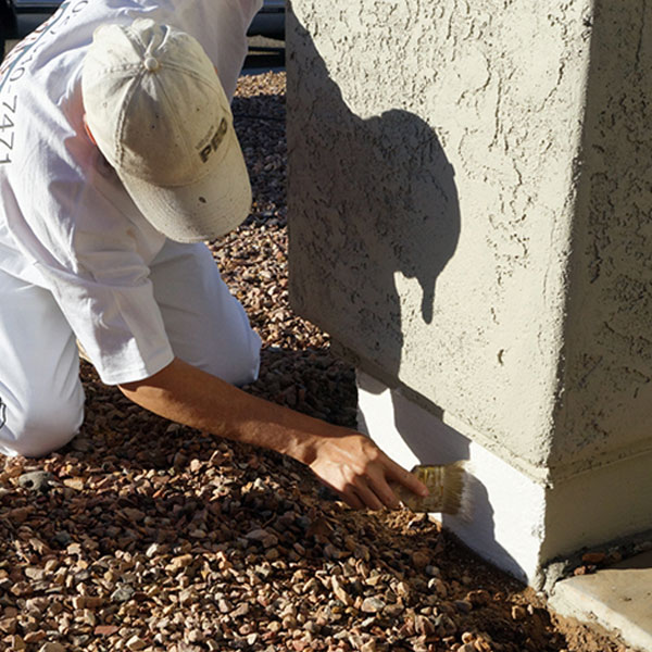 A painter brushes protective DRYLOK onto the stem wall of this pillar, ensuring the paint above is protected from ground moisture.