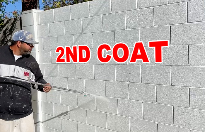 applying a second coat of paint to a brick wall